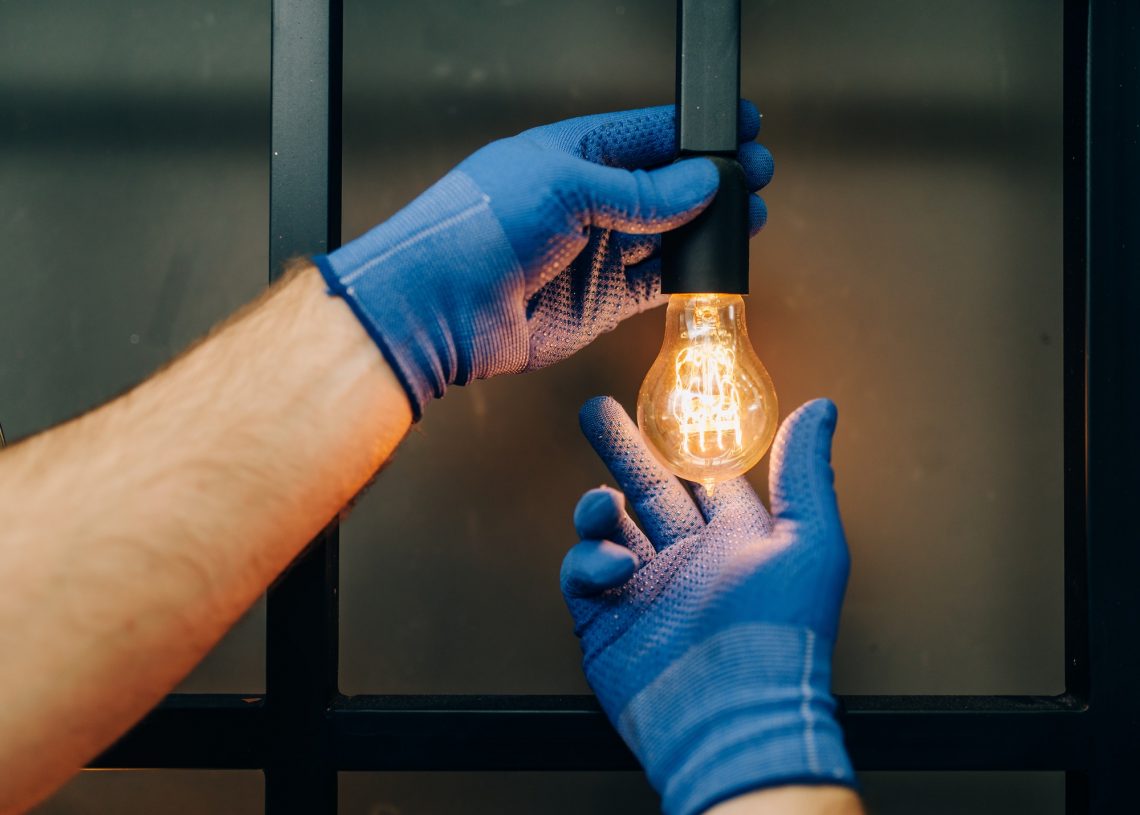 Electrician changes the light bulb, handyman